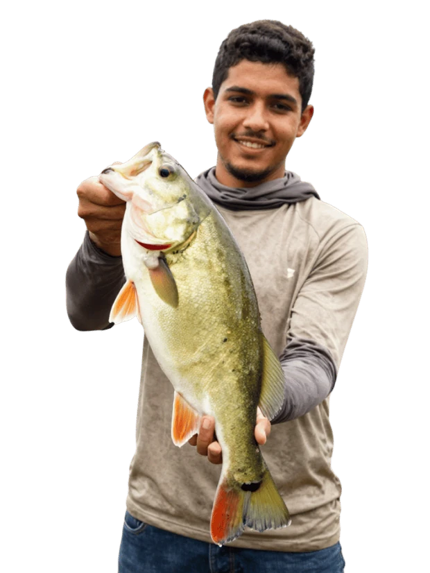 Jovem pescador sorrindo e segurando um peixe pego na sua pescaria